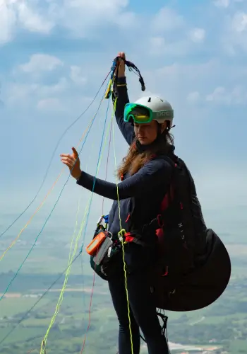 Eine Pilotin in den Startvorbereitungen. Geniesse den Blick über die grünen Hügel Kolumbiens während der Flugreise mit touch and go Paragliding und Airnomads Colombia.