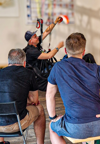 Der Fluglehrer zeigt. beim Manöverbriefing im Simulator während der Ausbildung bei touch and go Paragliding die Manöver vor.