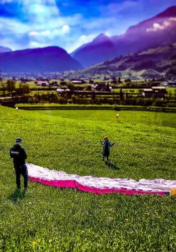 Der Teilnehmer des Teambuilding-Tages ist bereit, um zu seinem ersten kleinen Flug mit seinem Gleitschirm am Übungshang zu starten, begleitet von einem erfahrenen Fluglehrer von der Flugschule touch and go Paragliding.