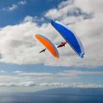 Zwei Nova Gleitschirme im Flug über der Zentralschweiz. Erlebe die Freiheit des Gleitschirmfliegens mit touch and go Paragliding.