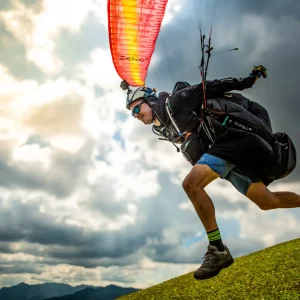 Gabor Kezi, ein Paragliding-Experte, startet mit seinem High-End-Cross-Country-Gleitschirm zu einem XC-Flug und zeigt dabei eine dynamische Bewegung und ein Lächeln.