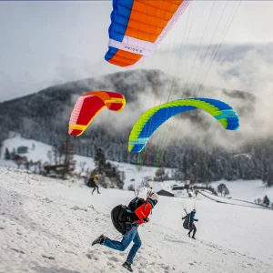 Drei Gleitschirme starten am Übungshang – eine perfekte Mischung aus Abenteuerlust, Spass und fundiertem Lernen bei touch and go Paragliding.