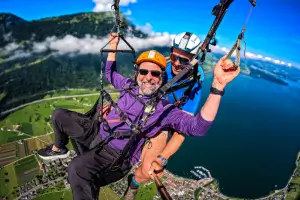 Flugschüler übernimmt das Steuer eines Tandemgleitschirms, während der Fluglehrer ihm Instruktionen gibt.