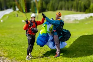 Flugschüler haben Spass am Landeplatz nach einer erfolgreichen Landung bei touch and go Paragliding.