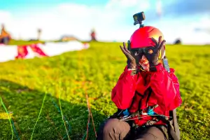 Pilotin am Startplatz lacht und albert, bevor sie mit ihrem Gleitschirm in den Himmel abhebt, umgeben von einer entspannten Atmosphäre.