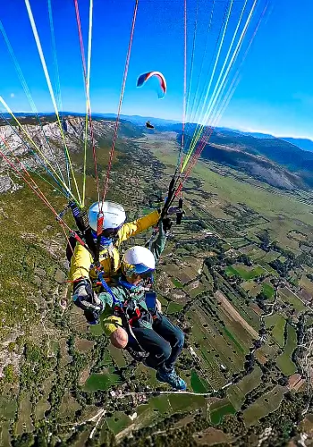 Gleitschirmpilot schwebt über den malerischen Hügeln Bosniens während der Bosnien Tour von touch and go Paragliding.