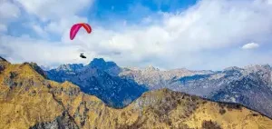 Paragliding pilots fly over the green hills and rocky mountains of Bassano del Grappa on an Easter excursion with touch and go Paragliding.
