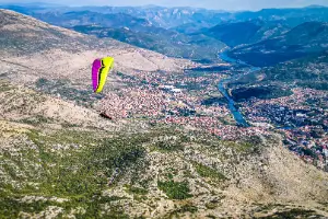 Gleitschirmpilot schwebt über den malerischen Hügeln Bosniens während der Bosnien Tour von touch and go Paragliding.