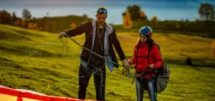 Fluglehrer kontrolliert die Leinen eines Gleitschirms am Übungshang während der Ausbildung bei touch and go Paragliding.