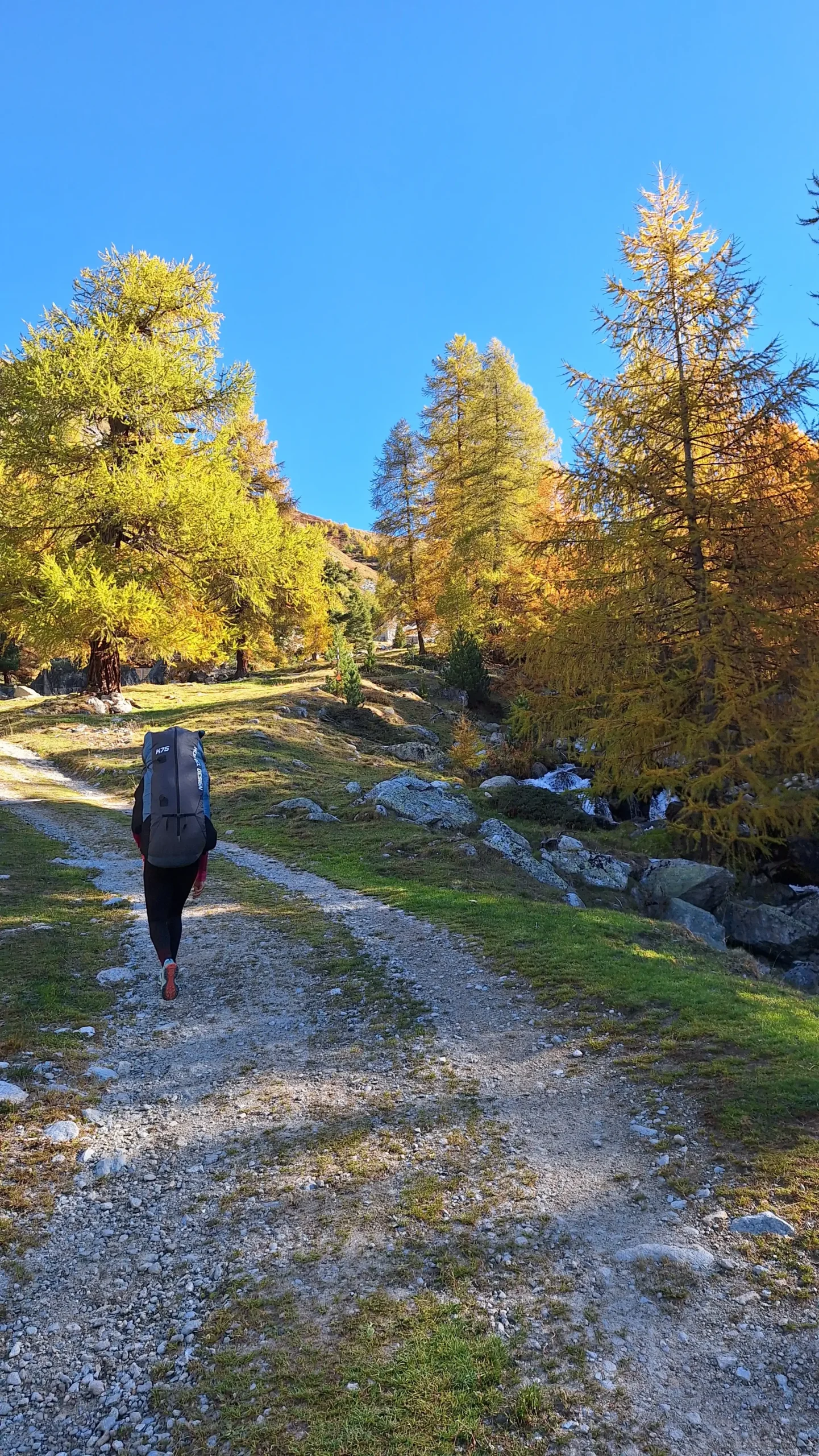Gleitschirmpilot wandert im Oberengadin mit seinem Gleitschirm auf einem Bergwanderweg zum Startplatz.