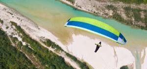 Gleitschirmflieger über dem smaragdgrünen Fluss Soca in Slowenien, mit Blick auf Berge und Natur